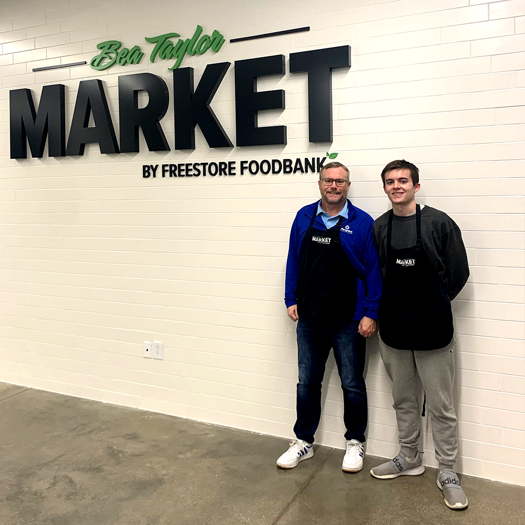 Associate Rich Vaughan and his son stand in front of the Bea Taylor Market Freestore Foodbank